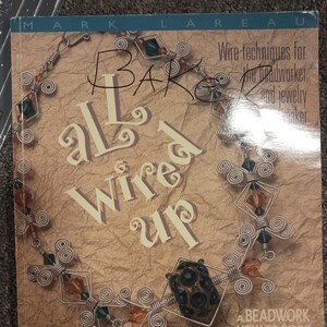 May include: A book cover titled "All Wired Up" with wire jewelry and the text "Wire techniques for the beadworker and jewelry maker." The cover features a necklace design with green, orange, and black beads.