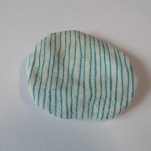 Puede incluir: Un círculo de tela blanca con rayas azules. La tela es suave y tiene una superficie ligeramente texturizada.