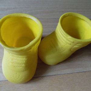 Puede incluir: Un par de botas de goma amarillas. Las botas están hechas de un material suave y flexible y tienen un diseño simple. Las botas están hechas en China.