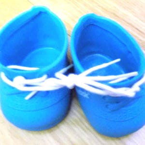 May include: A pair of bright blue baby shoes with white laces. The shoes are made of a soft material and have a classic sneaker design. The laces are tied together. The shoes are designed for infants.