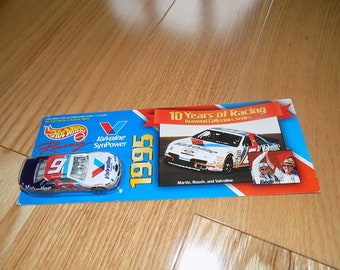May include: A white and blue 1995 Valvoline Ford Taurus NASCAR diecast car with the number 9 on the side. The car is on a blue and red card with the text "10 Years of Racing Diamond Collection Series" and "Martin, Roush, and Valvoline".