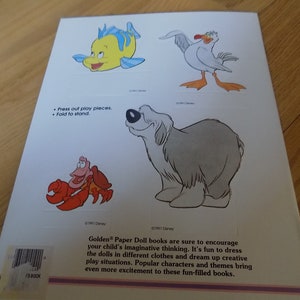 May include: A book cover with a white background and colorful illustrations of cartoon characters. The characters include a yellow fish, a white seagull, a red crab, and a gray dog. The text on the cover reads "Press out play pieces. Fold to stand."
