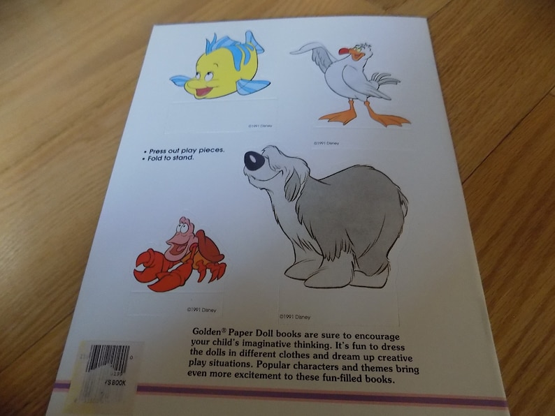 May include: A book cover with a white background and colorful illustrations of cartoon characters. The characters include a yellow fish, a white seagull, a red crab, and a gray dog. The text on the cover reads "Press out play pieces. Fold to stand."