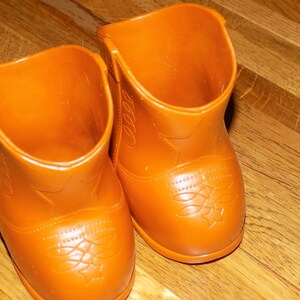 May include: A pair of brown plastic cowboy boots with a star design on the toe.