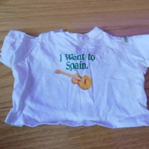 Puede incluir: Camiseta blanca con el texto "I Went to Spain." y una imagen de dibujos animados de una guitarra.