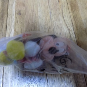 May include: A plush Mickey Mouse toy in a clear plastic bag. The toy is red, yellow, and white. The bag has a Disney logo on it.