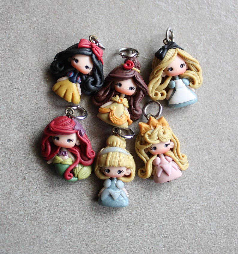 May include: A set of seven colourful princess-themed charms, each featuring a different Disney princess with a unique hairstyle and dress. The charms are made of polymer clay and have a silver loop for attaching to a necklace, bracelet, or keyring.