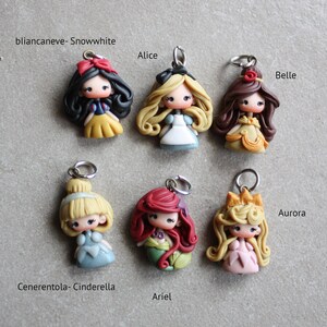 May include: Six handmade polymer clay charms featuring Disney princesses. The charms are Snow White, Alice, Belle, Cinderella, Ariel, and Aurora. Each charm has a silver loop for attaching to a necklace or bracelet.