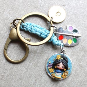 Llavero de técnica mixta: macramé, muñeca de arcilla polimérica y dije grabado a mano. Personalizable con letra.
