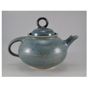 May include: A blue ceramic teapot with a black, looped handle on the lid.