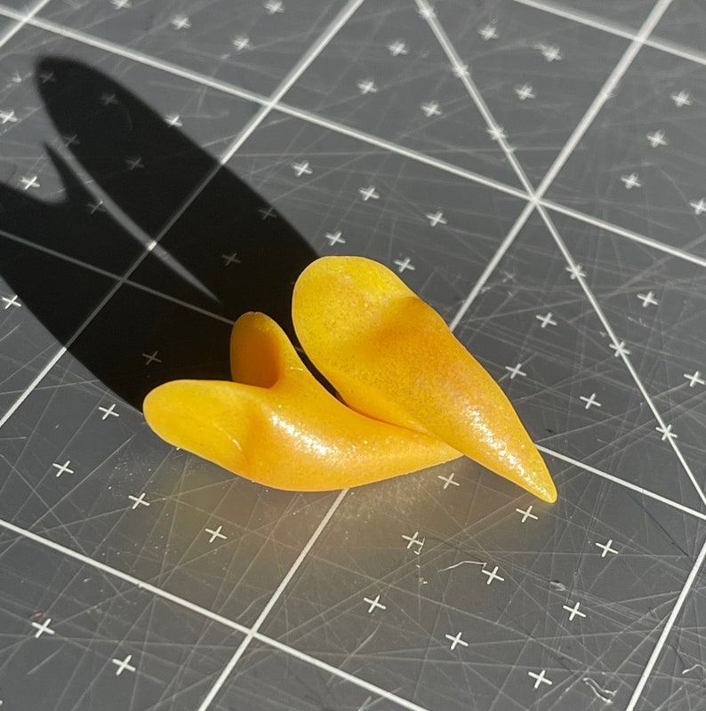 May include: Two yellow heart-shaped resin earrings with a pearlescent finish.