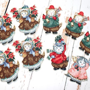 May include: Nine Christmas-themed felt appliques featuring cats wearing festive attire. The cats are holding poinsettias, bells, and holly.