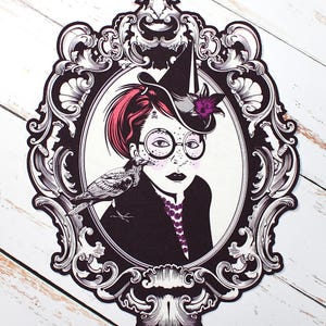 Może przedstawiać: Czarno-biała ilustracja kobiety w czarnym kapeluszu z fioletowym kwiatem, okularach i fioletowym naszyjnikiem. Trzyma w ręku czarnego ptaka. Ilustracja jest oprawiona w ozdobną czarną i białą ramę.