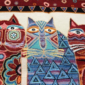 May include: A tapestry featuring three stylized cats with geometric patterns. The cats are in shades of red, blue, and green, with intricate details and a white background.