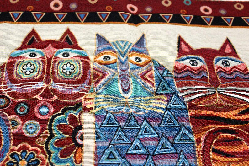 May include: A tapestry featuring three stylized cats with geometric patterns. The cats are in shades of red, blue, and green, with intricate details and a white background.