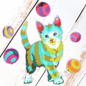 Puede incluir: Un parche de tela colorido con un gatito estilizado con rayas turquesas, verdes y marrones. El gatito tiene ojos morados y detalles en rosa. Varias bolas estampadas en tonos rosas, morados y amarillos rodean al gatito.