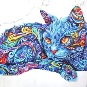 May include: A vibrant, stylized illustration of a cat in shades of blue, with intricate patterns in red, yellow, and green. The cat has orange eyes and a red nose, set against a white marble background. The artwork is detailed and colorful.