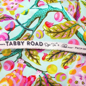 K&ouml;nnte beinhalten: Stoff mit einem farbenfrohen Blumen- und Katzenmuster. Der Stoff zeigt rosa, gelbe und lila Blumen sowie Katzen in verschiedenen Posen. Der Hintergrund ist hellblau. Der Text "TABBY ROAD" ist auf einem wei&szlig;en Band aufgedruckt.