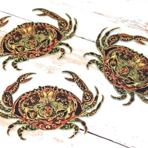 May include: Three embroidered fabric crab patches in shades of red, green, gold, and black. The crabs are detailed with intricate patterns and designs.