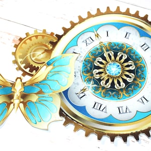May include: A gold and blue butterfly with a clock face in the background. The clock face has Roman numerals and a gold gear around the edge.