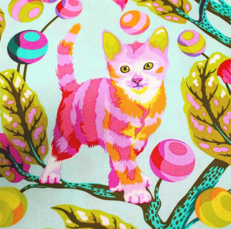 K&ouml;nnte beinhalten: Ein farbenfroher Stoff mit einer stilisierten Katze mit rosa, orangefarbenen und wei&szlig;en Streifen. Die Katze ist vor einem hellblauen Hintergrund mit skurrilen, farbenfrohen Kugeln und Bl&auml;ttern platziert. Das Design hat eine verspielte, k&uuml;nstlerische &Auml;sthetik.