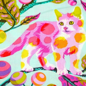 K&ouml;nnte beinhalten: Ein farbenfroher Stoff mit einer rosa Katze mit orangefarbenen und gelben Punkten auf hellblauem Hintergrund. Das Design umfasst stilisierte Bl&auml;tter und gemusterte Kugeln in verschiedenen Farben, wodurch ein skurriles, k&uuml;nstlerisches Muster entsteht.
