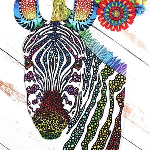 May include: A colorful zebra illustration with rainbow-colored stripes and a vibrant floral arrangement. The zebra's ears and nose are adorned with a spectrum of colors, creating a whimsical and eye-catching design. The artwork is set against a white wooden background.