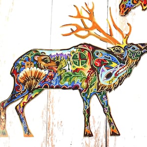 Può includere: Un'illustrazione stilizzata e colorata di un alce con dettagli intricati. L'alce è rappresentato in una tavolozza vibrante di blu, verdi, gialli e rossi, con una varietà di motivi e simboli incorporati nel suo design. Le corna dell'alce sono grandi e prominenti, e il suo corpo è adornato con una varietà di motivi floreali e geometrici.