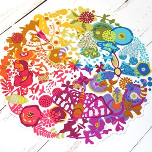 May include: A colorful round fabric design with a white background. The design features butterflies, flowers, and other abstract shapes in a rainbow of colors.