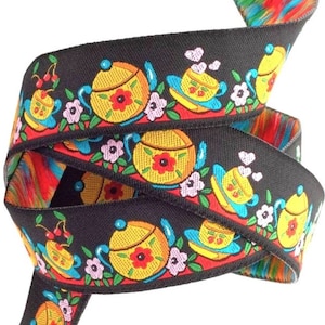 May include: Black ribbon with a repeating pattern of colorful teapots and cups with flowers and cherries. The ribbon is double-sided with a rainbow pattern on the reverse side.