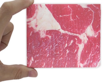 May include: Close-up of a raw beef steak with marbling and a red and white colour.