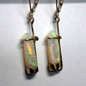 May include: A pair of gold earrings with a long, thin, iridescent opal stone set in each earring.