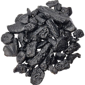 May include: A close-up of a pile of black tektite stones. The stones are irregular in shape and have a rough, textured surface.