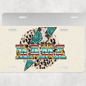 Puede incluir: Una placa de matrícula blanca y beige con un diseño de rayo marrón, negro y turquesa. La palabra "MAMA" está escrita en una fuente colorida con girasoles y acentos turquesa.