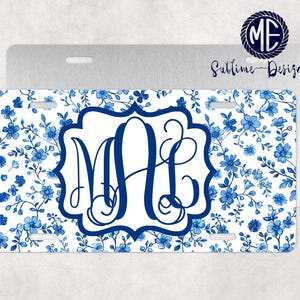 May include: A white personalized license plate with a blue floral pattern and a blue monogram in a decorative frame. The text "Sublime Design" is visible in the top right corner.