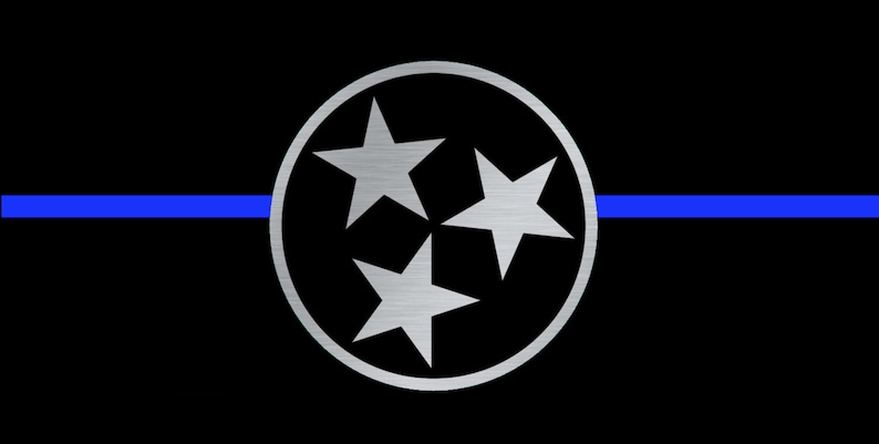 Op de afbeelding: Een zwart-blauwe vlag met een witte cirkel in het midden. De cirkel bevat drie zilveren sterren. De blauwe streep is een dunne lijn die over het midden van de vlag loopt.