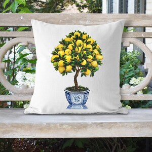 May include: White throw pillow with a printed image of a lemon tree in a blue and white planter. The tree has green leaves and yellow lemons.
