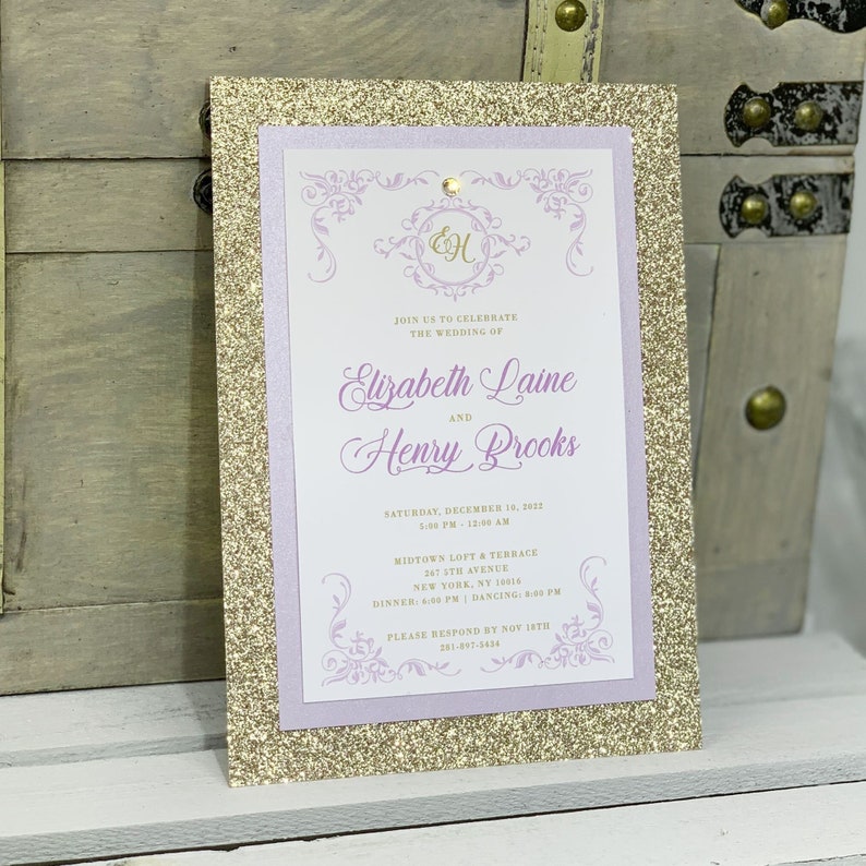 May include: Gold glitter wedding invitation with a purple border. The invitation features the names Elizabeth Laine and Henry Brooks, the date December 14, 2012, and the location Midtown Loft & Terrace, 247 5th Avenue, New York, NY 10016.