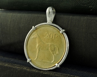 May include: A silver pendant featuring a 20p Irish coin with a horse design. The coin is set in a silver bezel and has a silver bail.