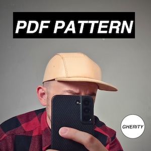May include: A tan leather five-panel cap with a flat brim. The text "PDF PATTERN" is displayed in a black rectangle above the cap. The word "GHERITY" is in a white circle in the lower right corner.