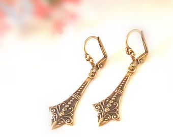 May include: A pair of gold-toned dangle earrings with a delicate floral design. The earrings have a hook closure.