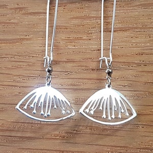 May include: A pair of silver dangle earrings featuring a delicate, fan-shaped design. The earrings have a simple, elegant style.