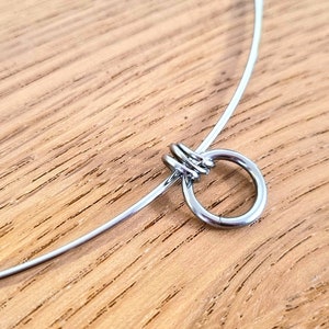 May include: A silver choker necklace with a small, round, silver charm.