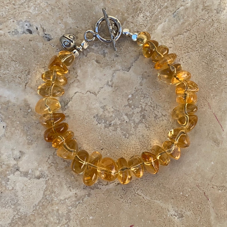 May include: A bracelet made of light brown, faceted gemstone beads with a silver toggle clasp.