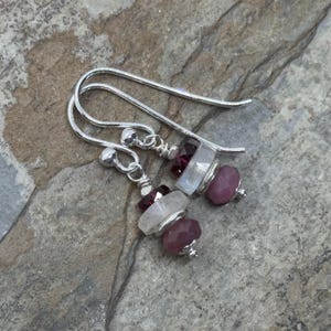 Può includere: Orecchini pendenti in argento con perline di pietre preziose rosa e bianche. Gli orecchini presentano un design a strati con una perla di pietra preziosa bianca al centro, circondata da perline di pietre preziose rosa.