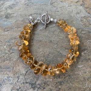 May include: A bracelet made of light brown, faceted gemstone beads with a silver toggle clasp.