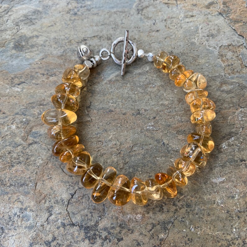 May include: A bracelet made of light brown, faceted gemstone beads with a silver toggle clasp.
