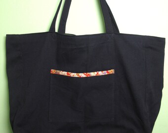 May include: A black canvas tote bag with a small pocket on the front. The pocket has a colorful floral trim.