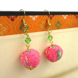 Peut inclure: Boucles d'oreilles en forme de boule en tissu rose et vert avec des accents dorés et des perles de cristal vertes.