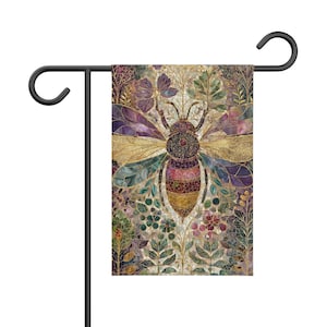 Puede incluir: Una bandera de jardín rectangular que presenta una ilustración central de una abeja con un patrón de estilo mosaico en tonos dorados, morados y verdes. La abeja está rodeada de intrincados motivos florales y botánicos, con efecto vitral.